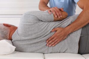 A pregnant woman receives a gentle spinal adjustment from a chiropractor in a softly lit clinic room.